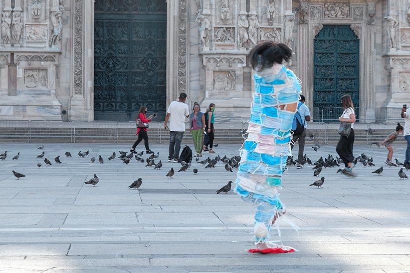 man wrapped by face masks struggles to move in no escape performance in milan, italy