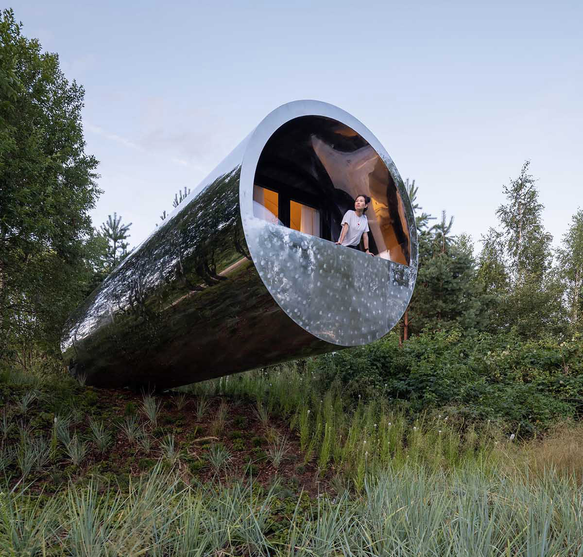 This Tube-Shaped Cabin With A Polished Metal Exterior Hovers Over The Surrounding Landscape