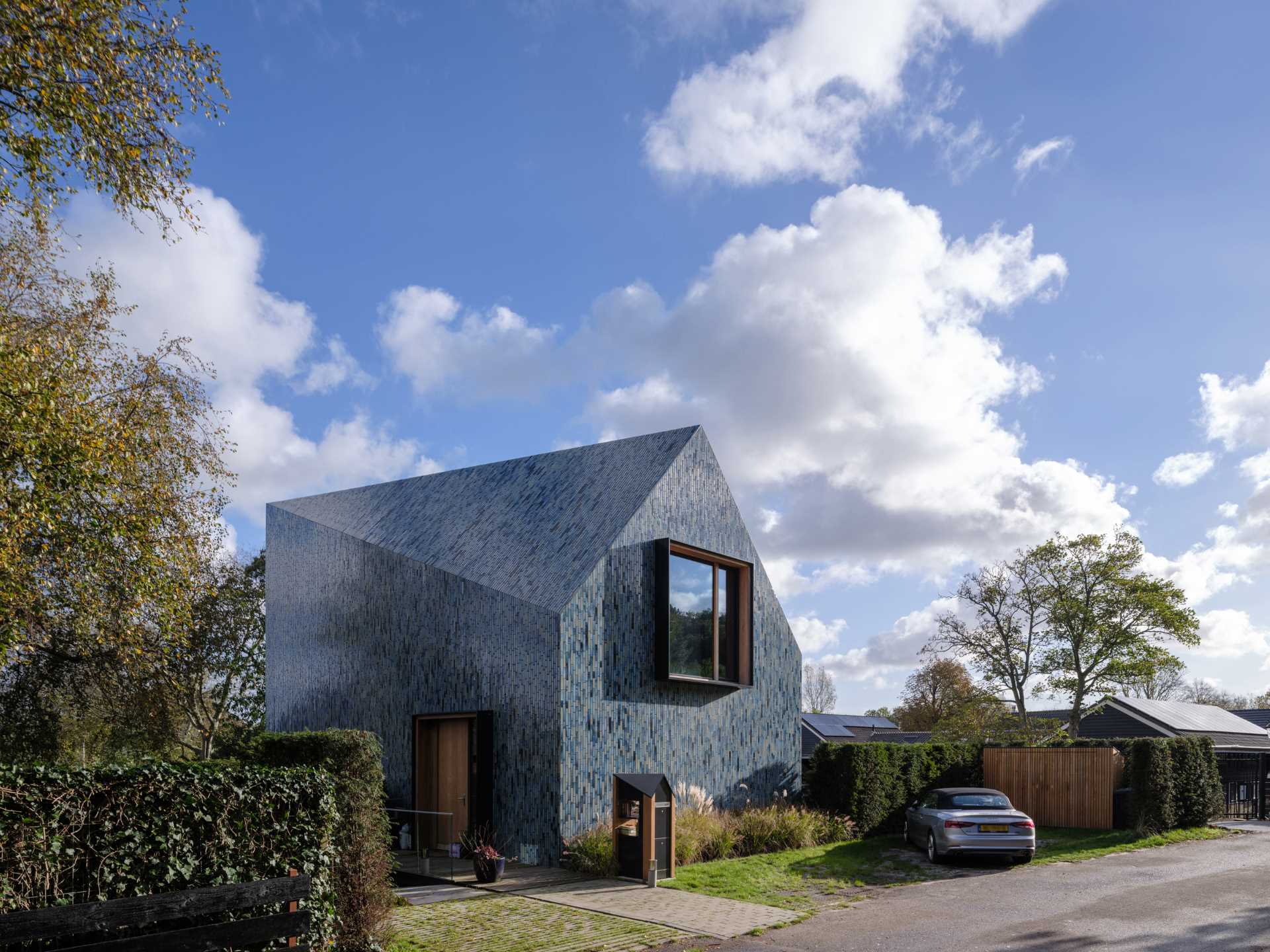Blue Tiles Cover The Exterior Of This House With A Twisted Roof