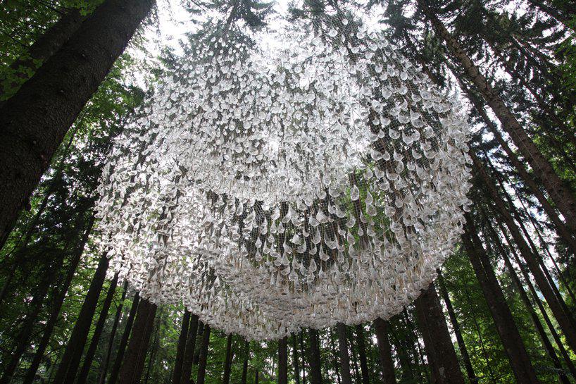 suspended among the trees, rainwater collecting sculptures mimic elaborate chandeliers